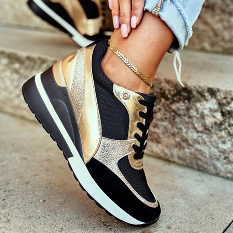 Plan rapproché de baskets noires et dorées élégantes avec une semelle à talon ergonomique, offrant confort et élégance. Portées avec un jean effiloché et un bracelet de cheville, ces chaussures allient design chic et fonctionnalité pour un look tendance au quotidien.