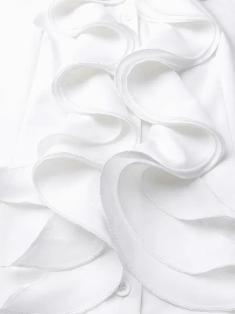 Gros plan sur les volants élégants en tissu blanc fluide, détail raffiné apportant une touche féminine et sophistiquée à ce chemisier chic.