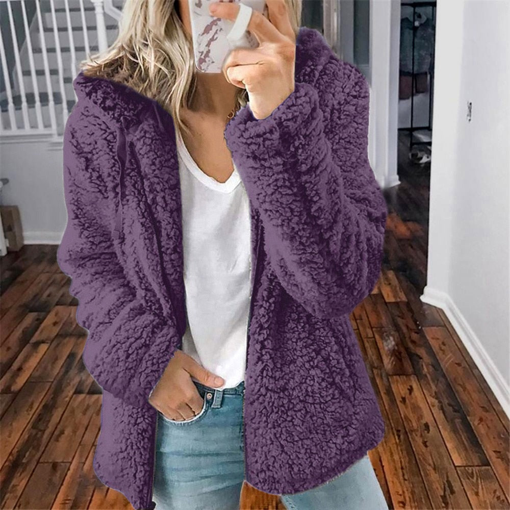 Femme portant la veste d’hiver courte Marie en fausse fourrure chaude, couleur violet, associée à un t-shirt blanc et un jean, pour un style cosy et original.
