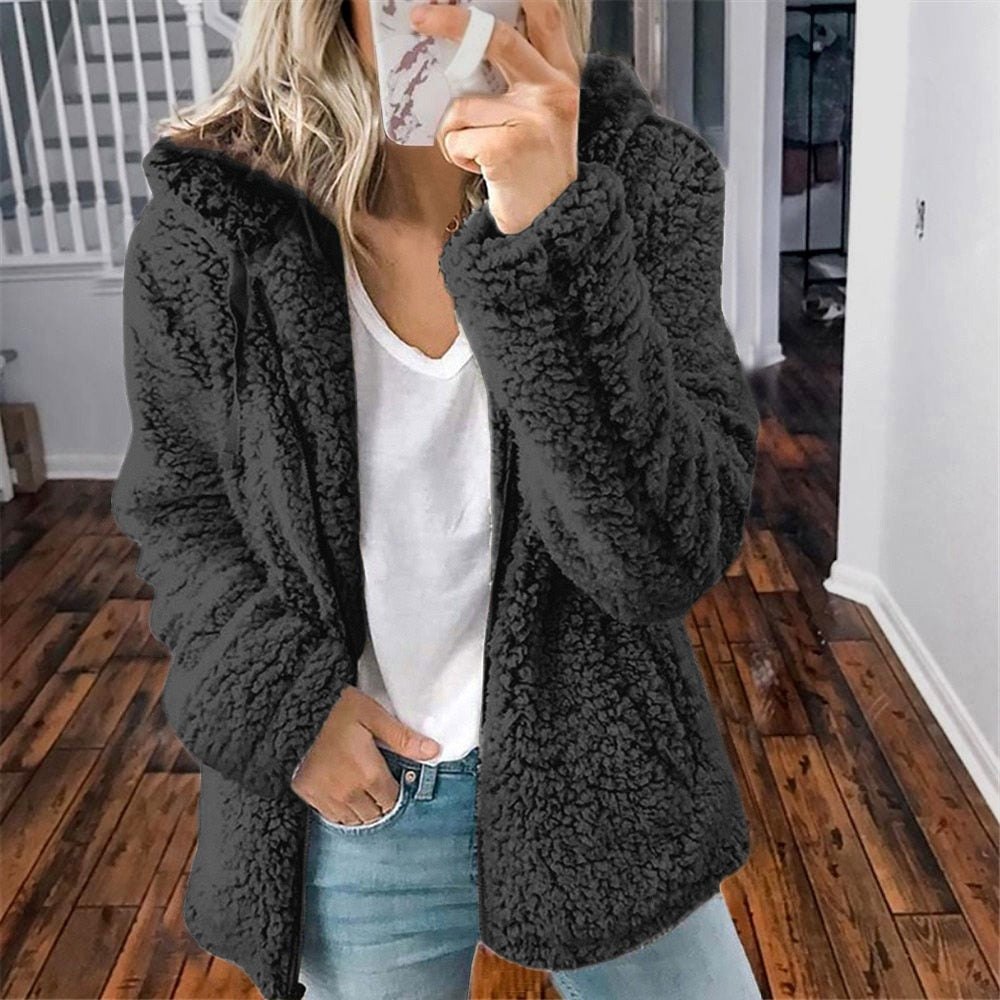Femme portant la veste d’hiver courte Marie en fausse fourrure chaude, couleur noir, associée à un t-shirt blanc et un jean, pour un style chic et décontracté.