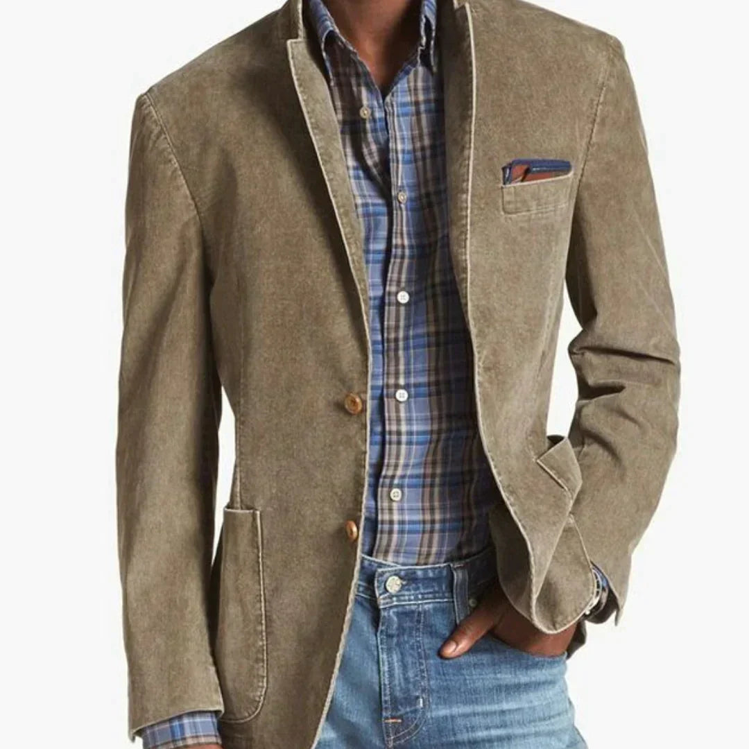 Un homme porte un blazer beige décontracté, avec une chemise à carreaux bleus et verts. Le blazer est ajusté et possède un mouchoir de poche élégant. Il est complété par un jean clair, offrant une tenue à la fois élégante et décontractée.
