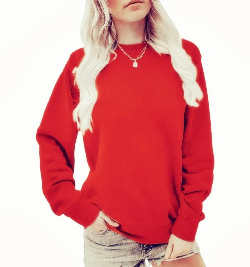 Femme portant un sweat-shirt rouge vif à manches longues, avec un col rond. Elle a des cheveux blonds et porte un collier délicat, associant le sweat avec un short en jean. Elle pose une main sur sa taille.