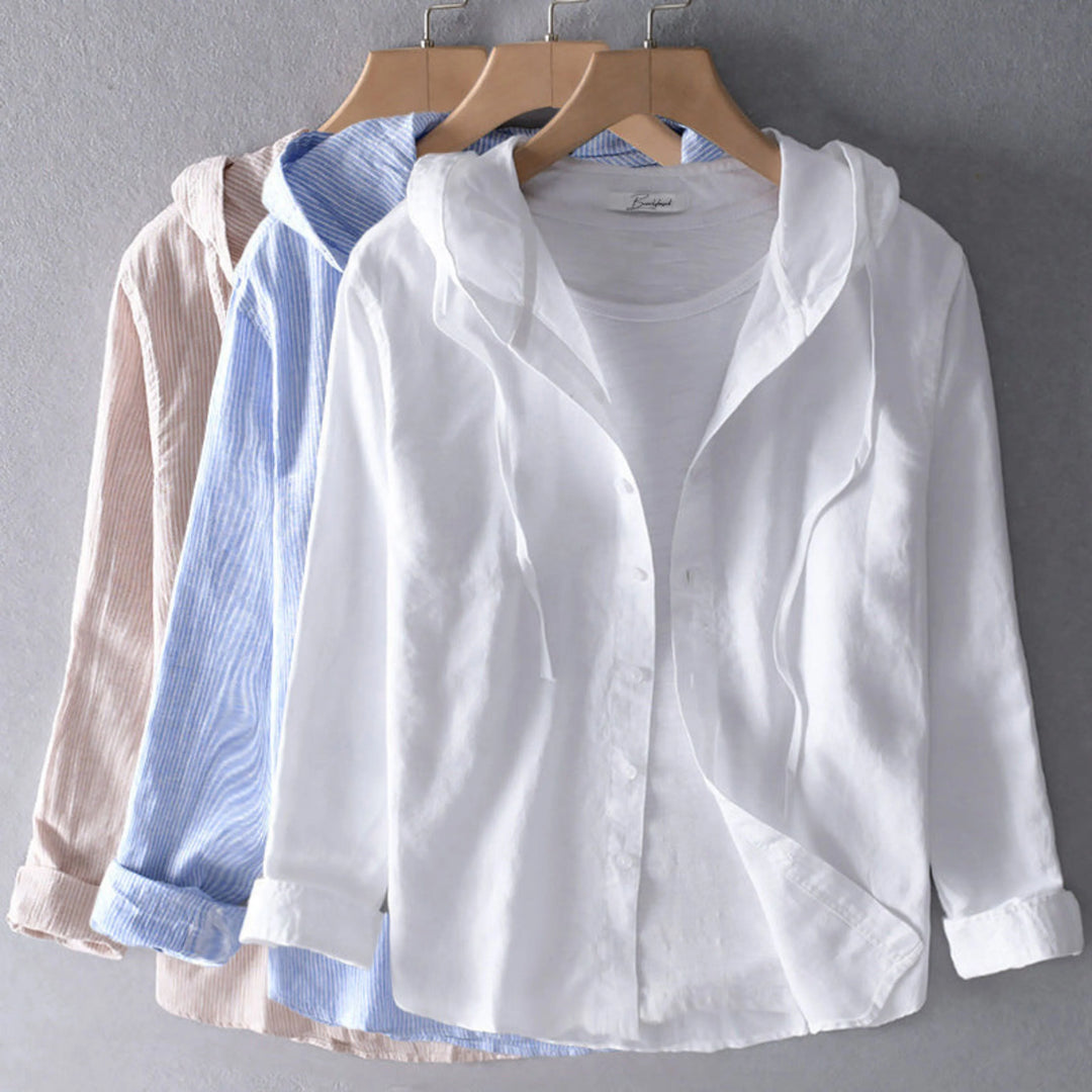 Blouse légère à capuche, boutonnée, présentée sur cintre en blanc avec deux autres coloris (bleu rayé et beige) en arrière-plan.