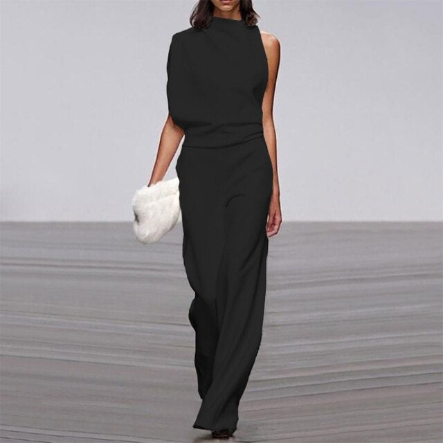 Abette | Combinaison chic pour femme en noir, asymétrique avec un haut sans manches et un pantalon fluide à jambes larges, idéal pour une soirée élégante, accompagné d'un sac à main en fourrure blanche.