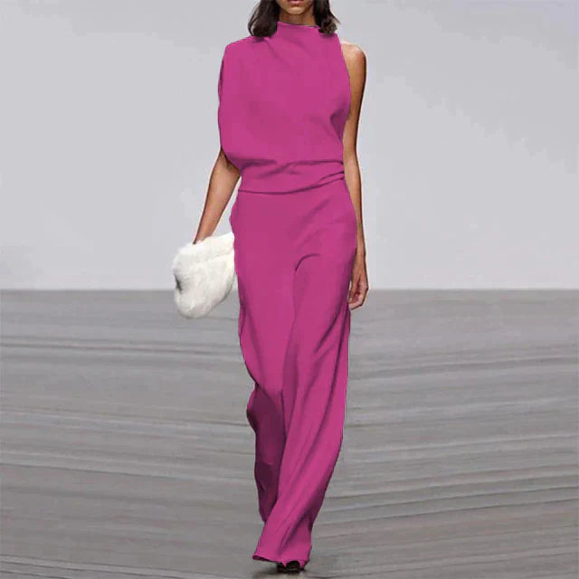 Abette | Combinaison chic pour femme, élégante et moderne en couleur fuchsia avec une coupe asymétrique et un pantalon fluide à jambes larges, parfaite pour une soirée, accompagnée d'un sac à main en fourrure blanche.