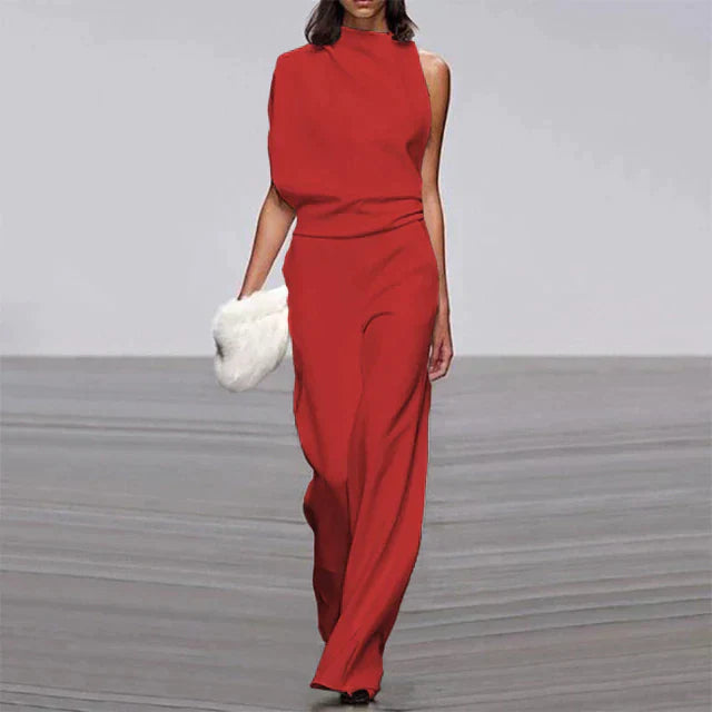 Abette | Combinaison chic pour femme, élégante et moderne, de couleur rouge avec une coupe asymétrique, idéale pour une soirée, avec un pantalon à large jambe et un sac à main en fourrure.