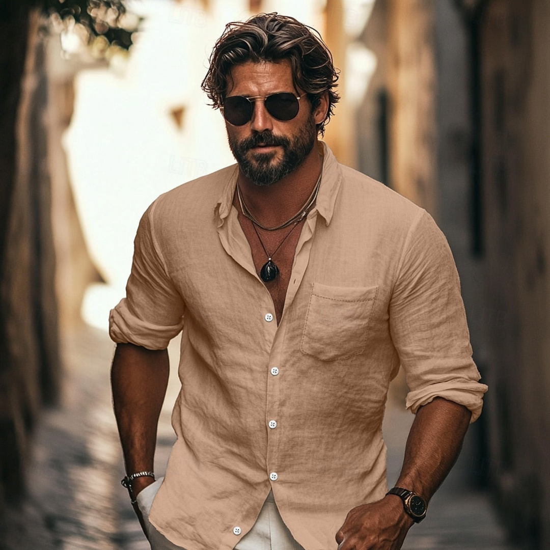 Homme portant la chemise d’été boutonnée Alban beige sable, tissu léger et respirant, manches retroussées et col ouvert, look estival chic avec lunettes de soleil.