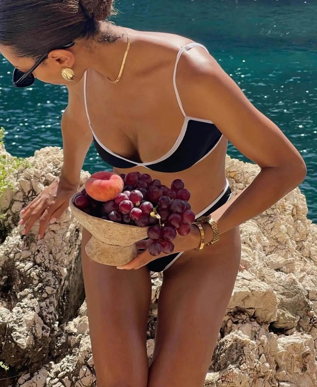Bikini moderne pour femme Alice ensemble deux pièces noir à bordures contrastées, avec haut à fines bretelles et bas échancré, porté en bord de mer avec des accessoires élégants pour un style estival raffiné.