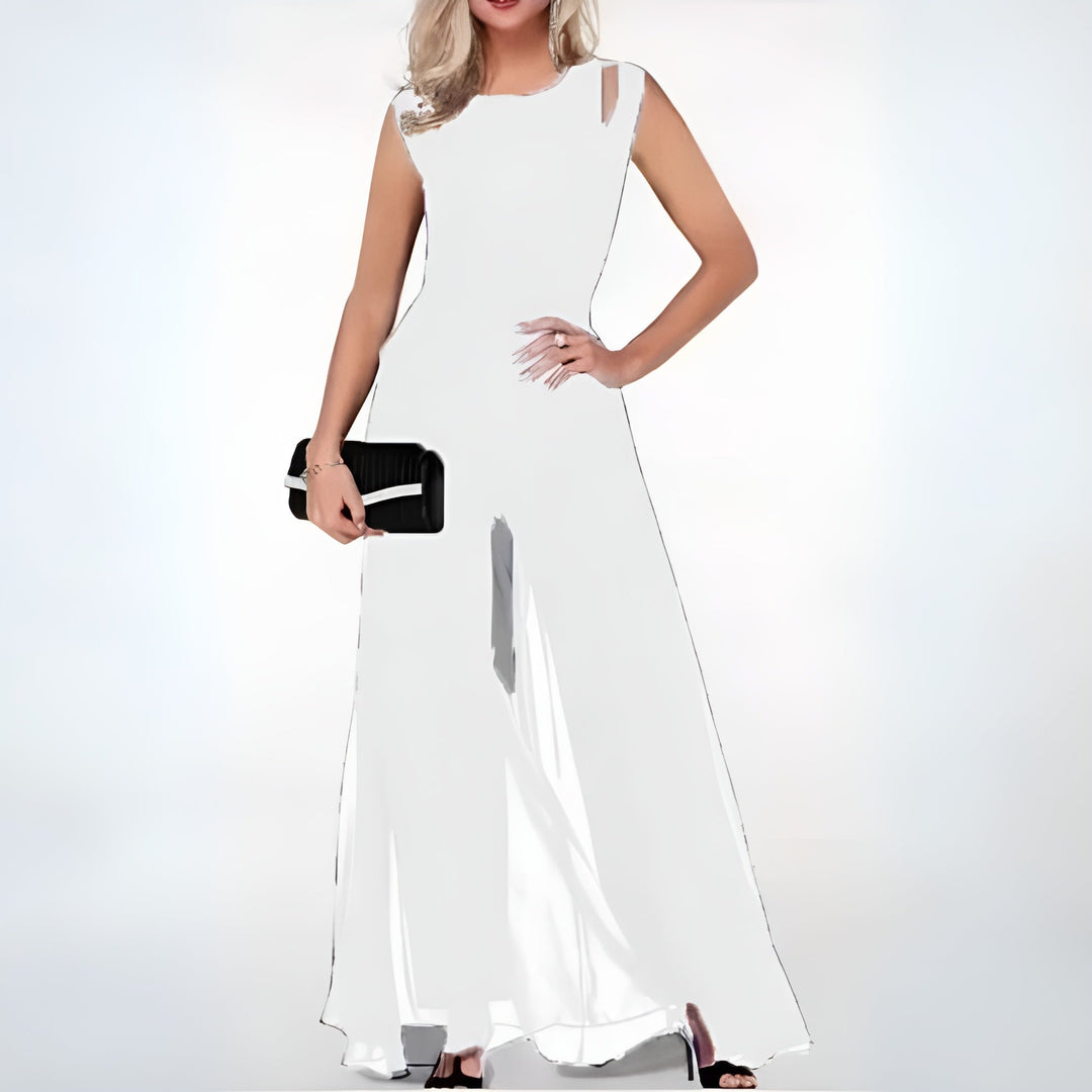 Combinaison longue blanche sans manches avec jambes larges en voile fluide, portée avec talons et pochette noire.