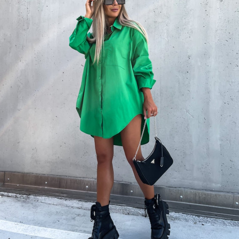 Chemisier oversize vert pour femme au style tendance, avec coupe ample, manches longues retroussées et fermeture boutonnée, porté avec bottines noires et sac à main noir pour un look moderne et audacieux.