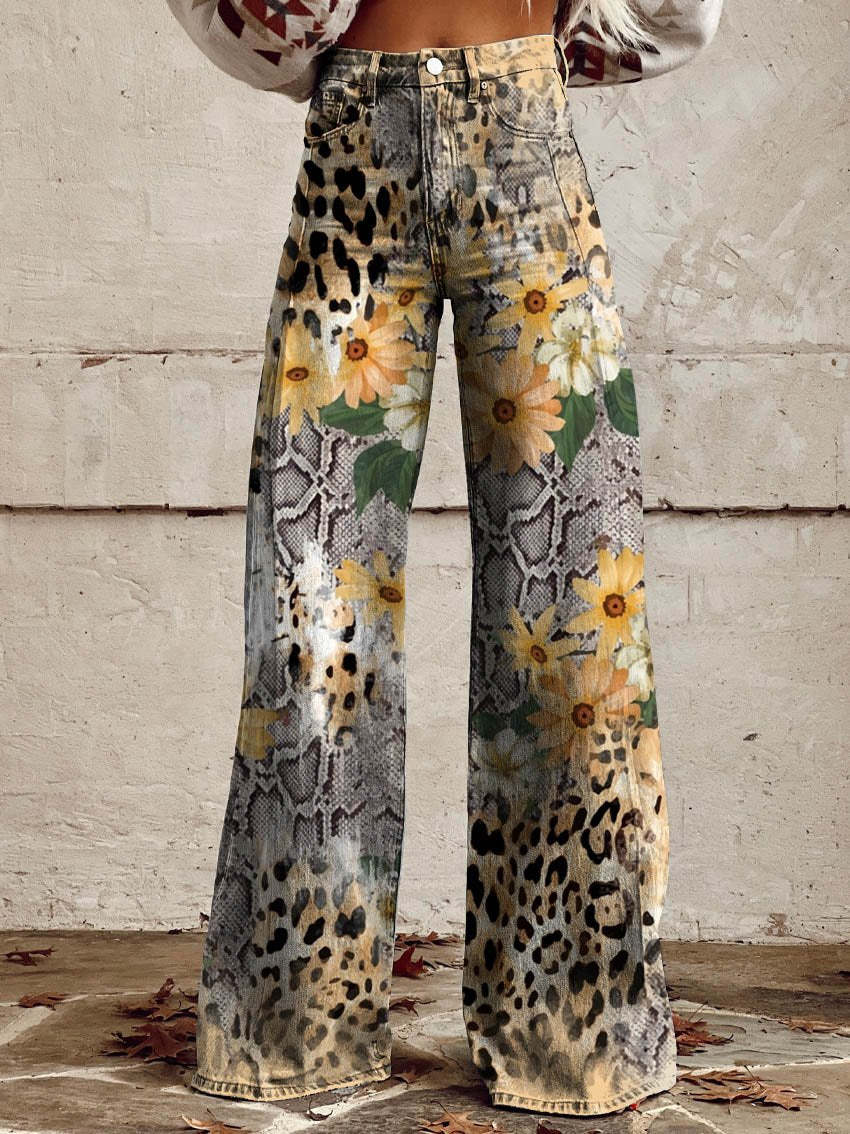 Jean ample pour femme Anouk taille haute, imprimé mixte léopard, effet python et fleurs jaunes, coupe large et jambes évasées, porté devant un mur en béton.