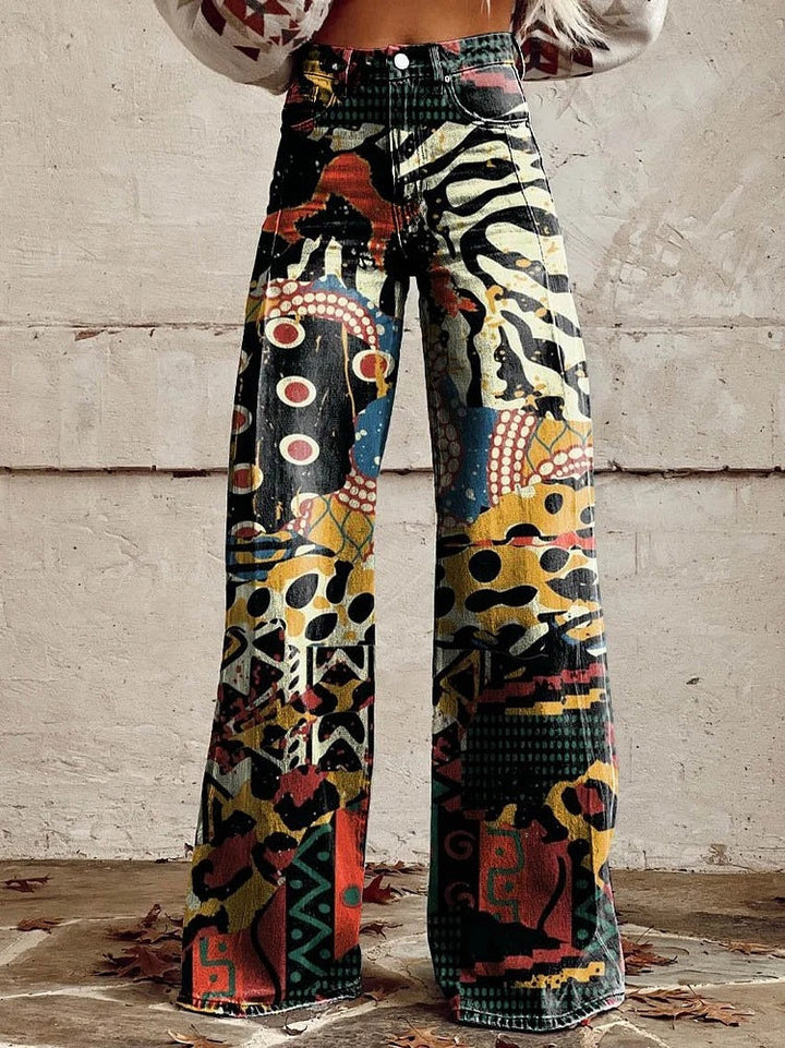 Jean ample pour femme Anouk taille haute, denim noir à imprimé patchwork multicolore avec motifs graphiques et animal print, coupe large et jambes évasées, porté devant un mur en béton.
