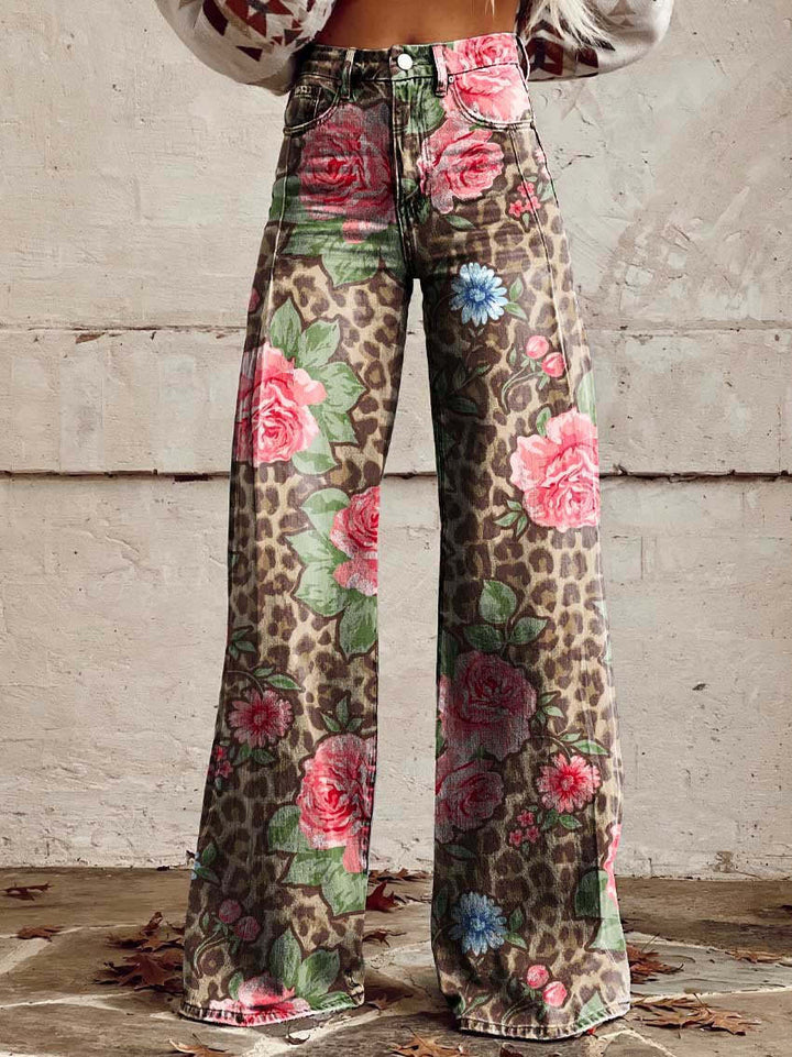 Jean ample pour femme Anouk taille haute, imprimé léopard marron avec grandes roses roses et fleurs bleues, coupe large et jambes évasées, porté devant un mur en béton.