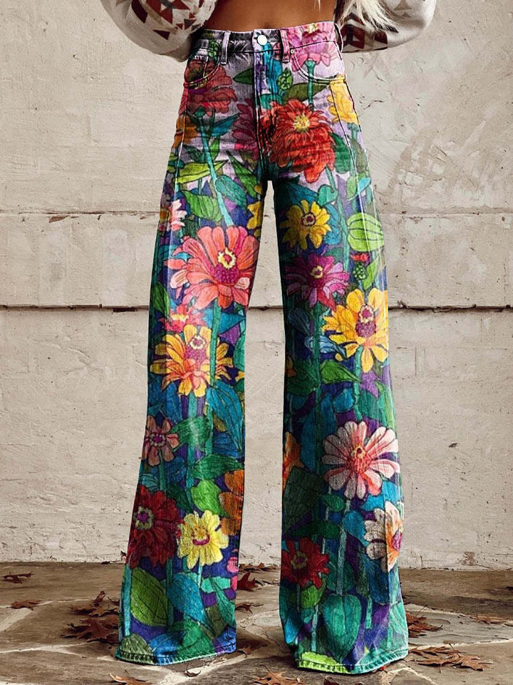 Jean ample pour femme Anouk taille haute, denim multicolore à imprimé fleurs et feuillage façon collage, coupe large et jambes évasées, porté devant un mur en béton.