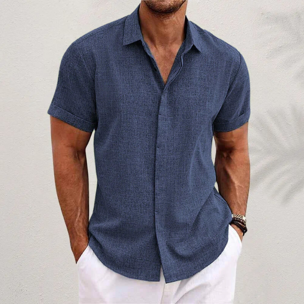 Chemise en lin moderne pour homme, modèle Antoine, de couleur bleu marine, à manches courtes, coupe ajustée, parfaite pour un style élégant et décontracté avec un pantalon clair.