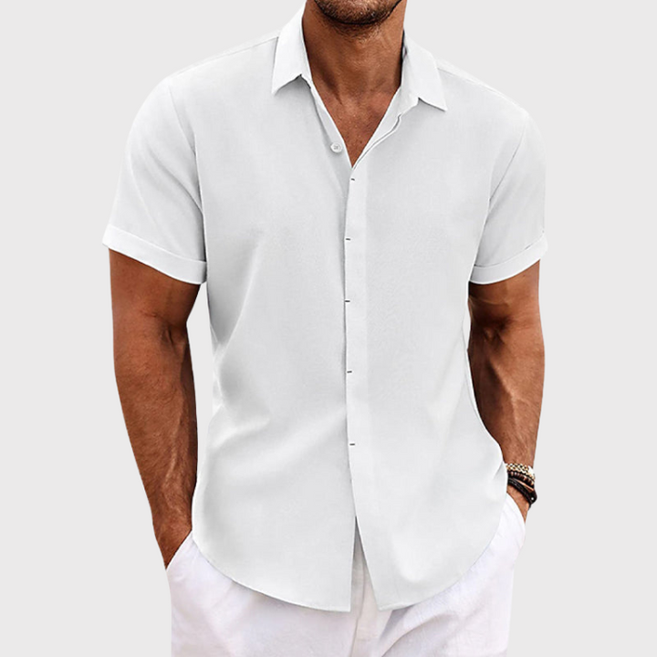 Chemise en lin moderne pour homme, modèle Antoine, de couleur blanc cassé, à manches courtes, coupe ajustée, parfaite pour un look élégant et estival avec un pantalon clair.