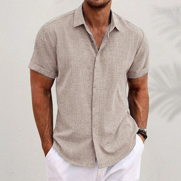 Chemise en lin moderne pour homme, modèle Antoine, de couleur beige clair, à manches courtes, coupe ajustée, portée avec un pantalon blanc pour un style élégant et décontracté.