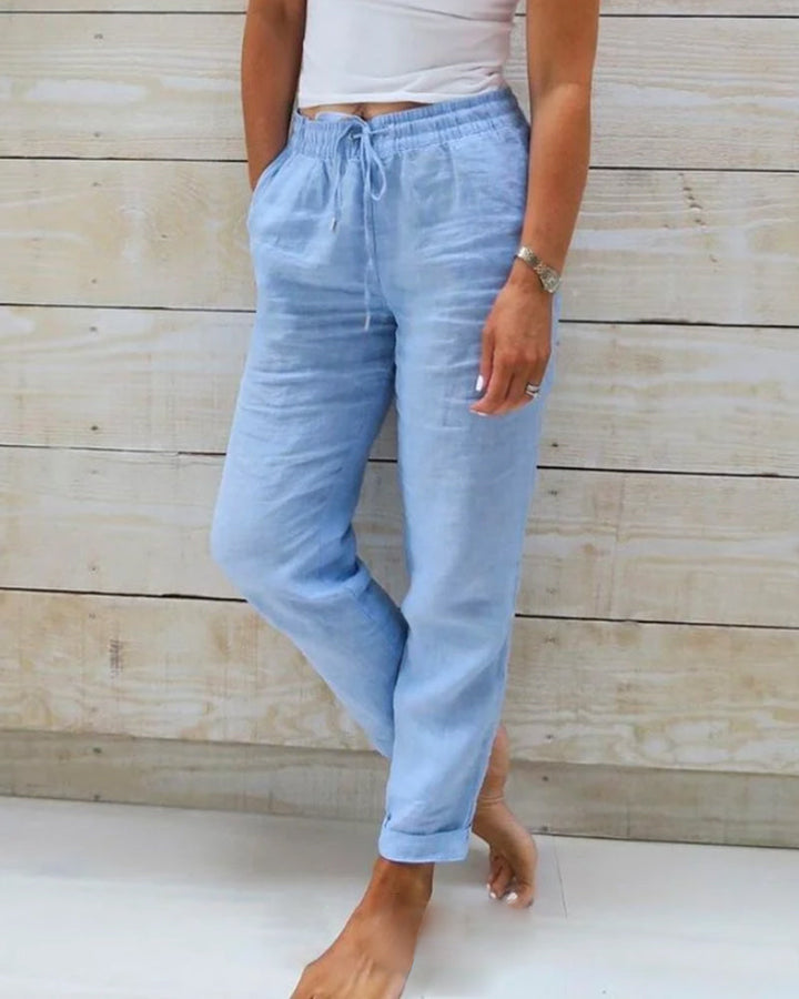 Pantalon léger pour femme de couleur bleu clair, avec une taille élastiquée et un cordon de serrage. Le pantalon a une coupe décontractée et élégante, parfait pour une tenue moderne et confortable.