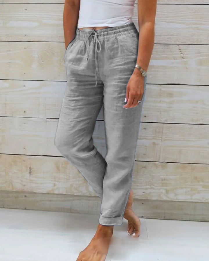 Pantalon gris clair pour femme avec une taille élastiquée et un cordon de serrage, offrant une coupe décontractée et confortable. Parfait pour un look moderne et élégant, adapté à une tenue quotidienne décontractée.
