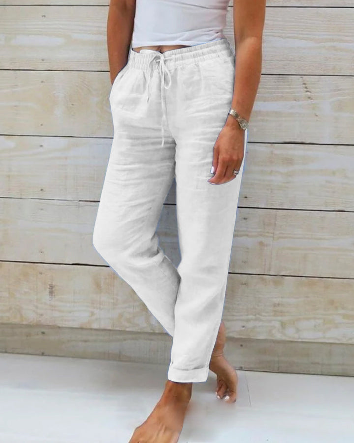Pantalon blanc pour femme avec une taille élastiquée et un cordon de serrage, offrant une coupe décontractée et confortable. Parfait pour un look frais et élégant, idéal pour une tenue simple et stylée au quotidien.