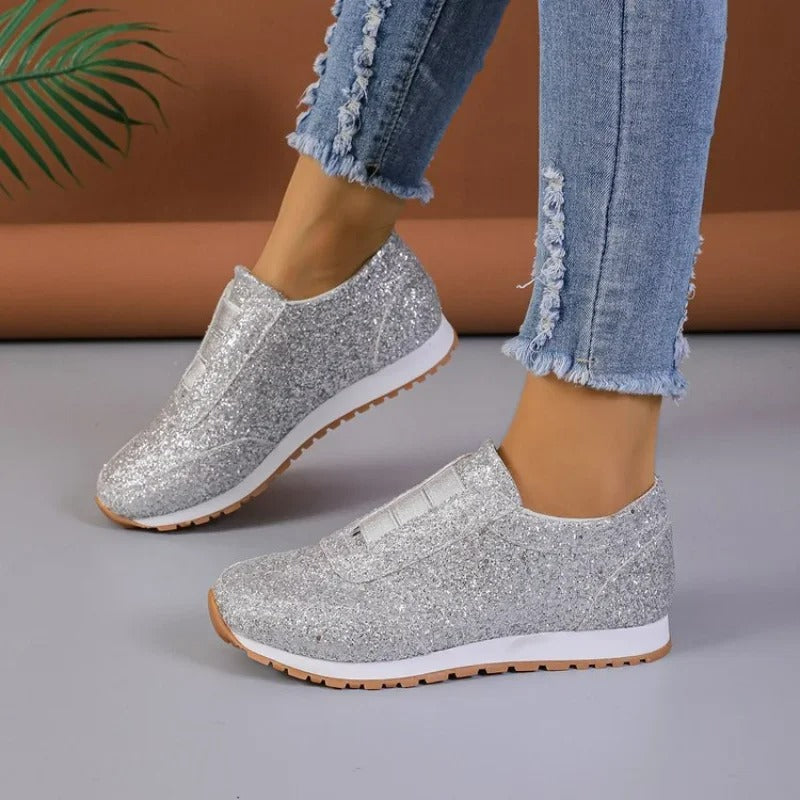 Baskets argentées à paillettes, profil latéral, semelle blanche avec crampons beige, portées avec un jean.