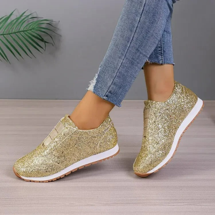 Baskets femme dorées à paillettes, semelle blanche et gomme, portées avec un jean bleu, vue de trois quarts.