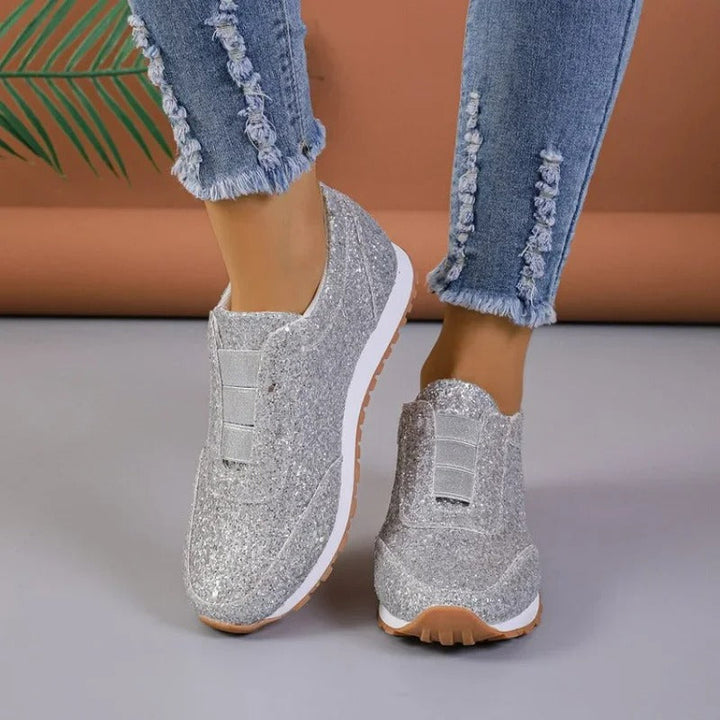 Baskets argentées scintillantes avec semelle blanche, portées avec un jean bleu effiloché.