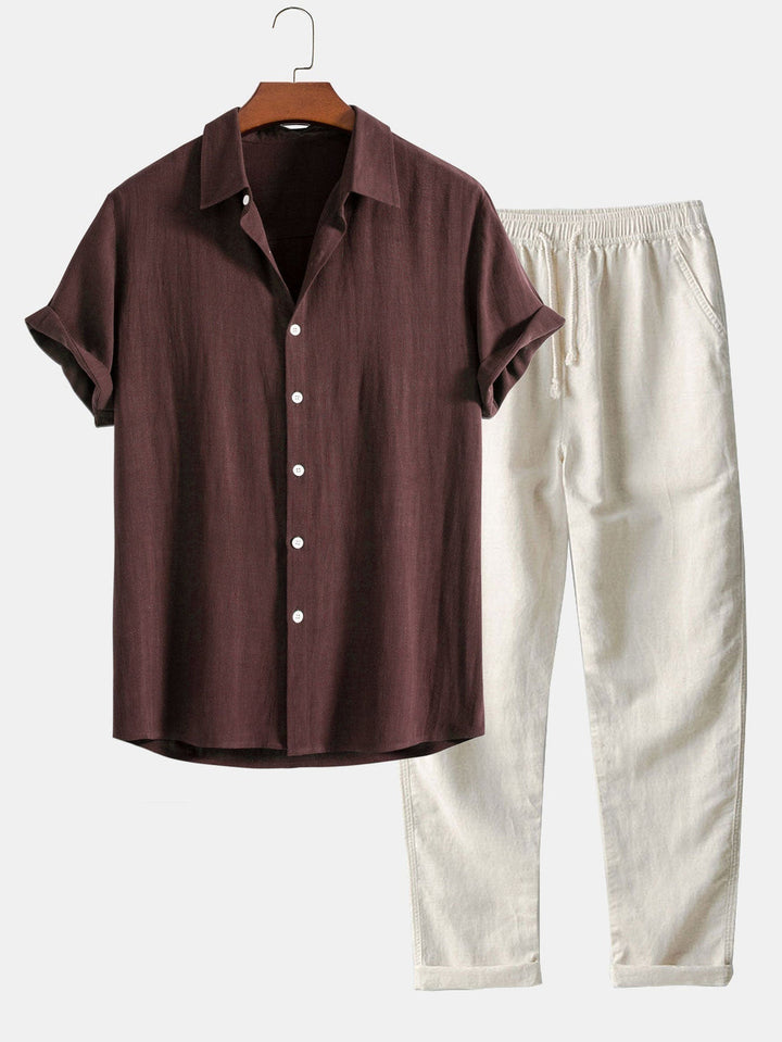 Un ensemble chic et décontracté composé d'une chemise à manches courtes de couleur bordeaux, avec des boutons blancs, et d'un pantalon beige clair à la coupe moderne, parfait pour un look estival à la fois élégant et confortable.