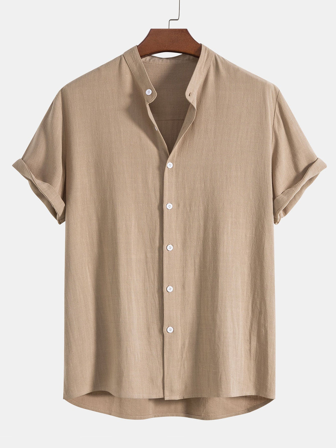 Chemise légère et décontractée de couleur beige avec des manches courtes roulées, dotée de boutons blancs et d'un col minimaliste. Idéale pour un look estival élégant et confortable.