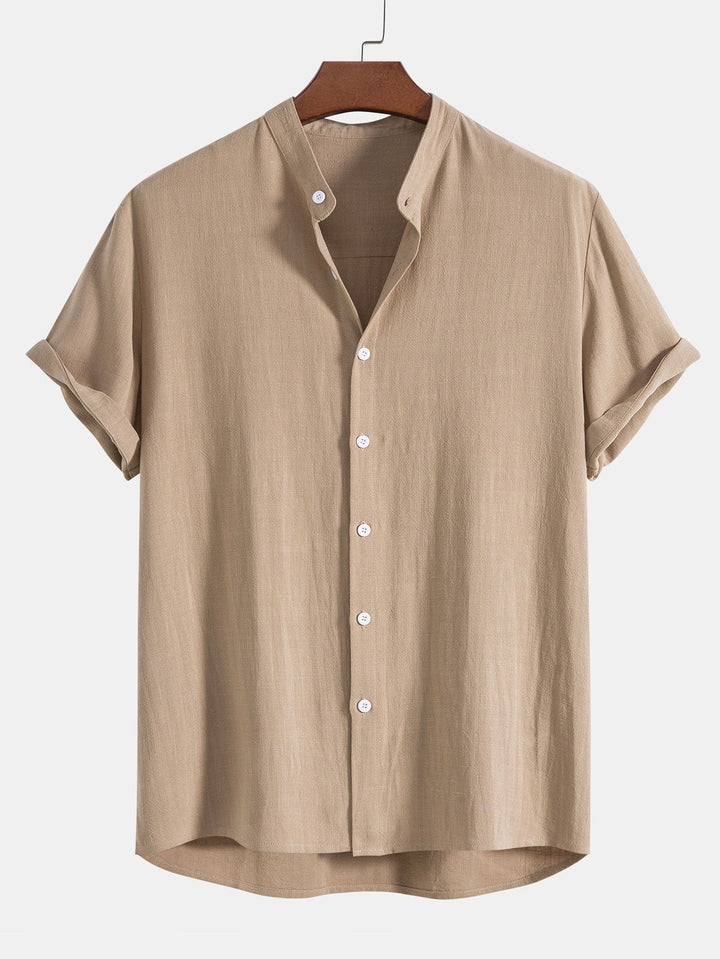 Chemise légère et décontractée de couleur beige avec des manches courtes roulées, dotée de boutons blancs et d'un col minimaliste. Idéale pour un look estival élégant et confortable.