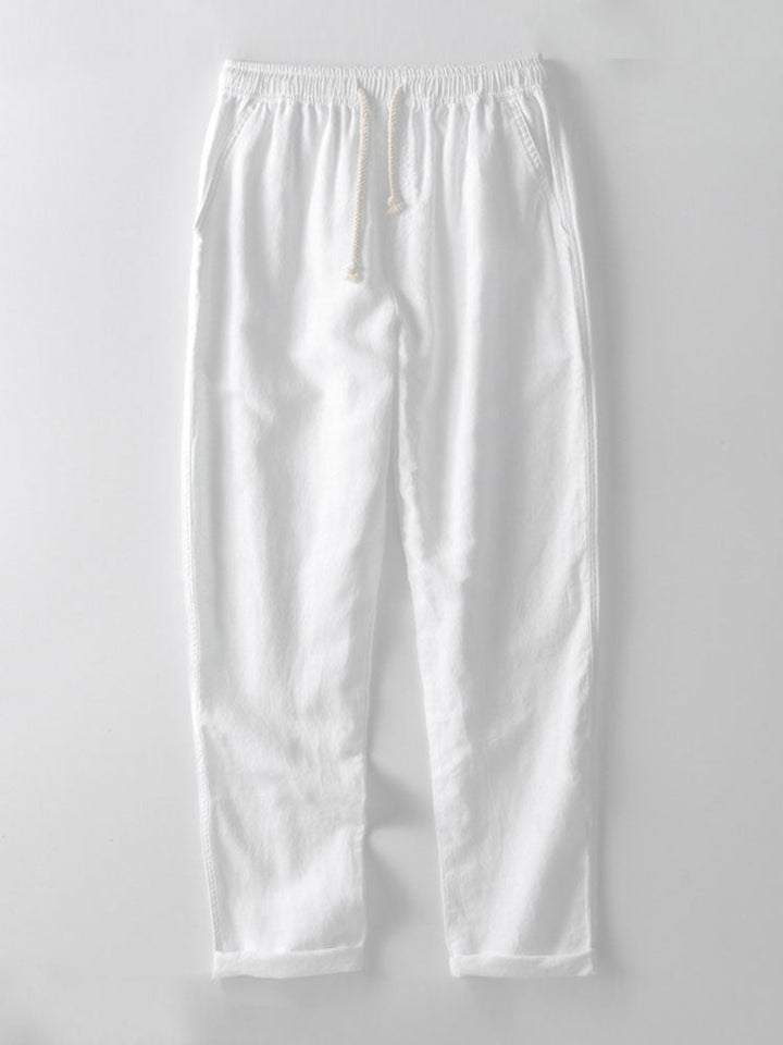 Pantalon d'été léger et confortable de couleur blanche, avec une taille élastique et des cordons de serrage. Parfait pour compléter une tenue estivale élégante et décontractée.