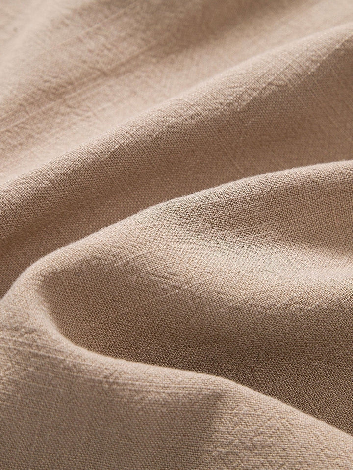Zoom sur le tissu beige de haute qualité, offrant une texture douce et légère, idéale pour un confort optimal pendant l'été. Parfait pour une tenue élégante et décontractée.