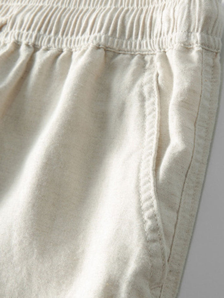 Détail du pantalon beige clair montrant la taille élastique et les poches latérales, offrant un confort optimal et une coupe moderne pour un look estival décontracté et pratique.