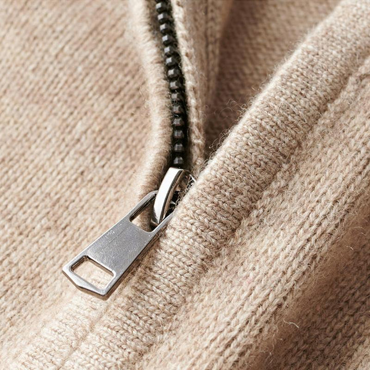 Gros plan du pull zippé pour hommes Basile, en maille beige, mettant en valeur la fermeture éclair métallique et la texture douce du tissu.