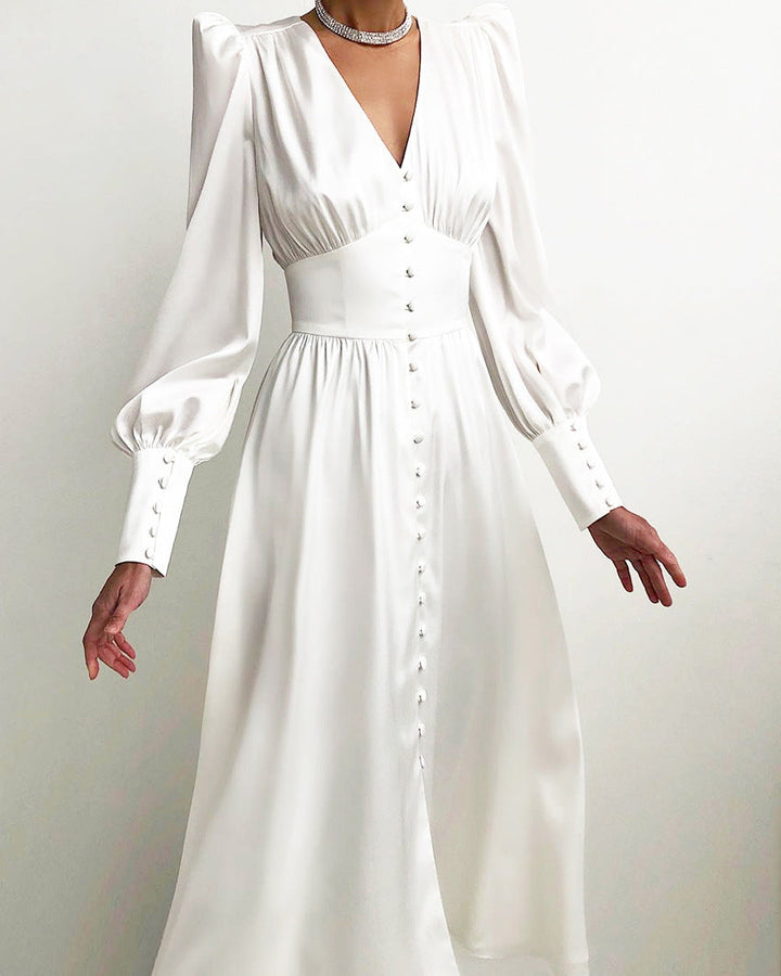 Robe en blanc éclatant, avec un décolleté en V, des manches longues bouffantes et des boutons décoratifs sur le devant, idéale pour une soirée élégante ou un événement formel.