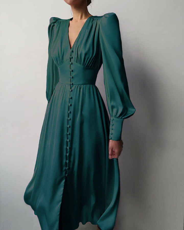 Robe en satin vert émeraude, avec des manches longues bouffantes, un décolleté en V et des boutons décoratifs sur le devant, idéale pour une soirée élégante ou un événement spécial."