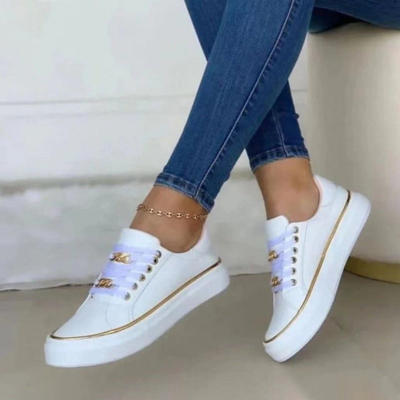 Baskets plateforme pour femme Blanche blanches, style moderne avec lacets et détails dorés, portées avec un jean bleu sur fond clair.