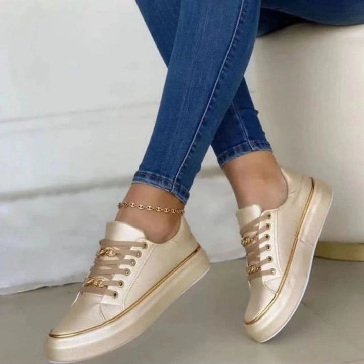 Baskets plateforme pour femme Blanche beige/crème, style moderne avec bordures et détails dorés, portées avec un jean bleu sur fond clair.
