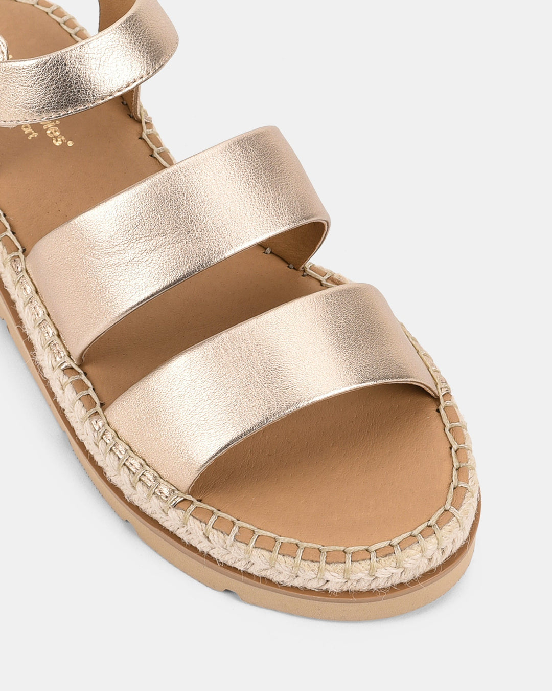 Zoom sur les sandales compensées dorées pour femmes, modèle Cady. Détails des trois bandes métalliques et de la semelle tissée en corde, offrant un look tendance et une grande confortabilité.