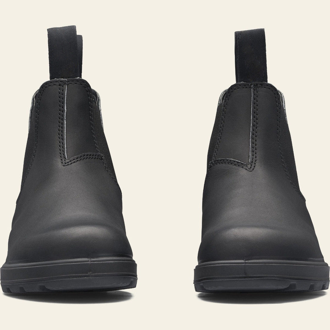 Vue de face de deux bottines noires en cuir lisse, affichant un design minimaliste et moderne. Leur silhouette présente une tige montante avec des empiècements élastiques latéraux et des languettes de tirage à l’avant et à l’arrière pour faciliter l’enfilage. Les semelles épaisses offrent une adhérence solide et une finition mate donne à ces chaussures un style élégant et intemporel, parfait pour un usage quotidien ou professionnel.