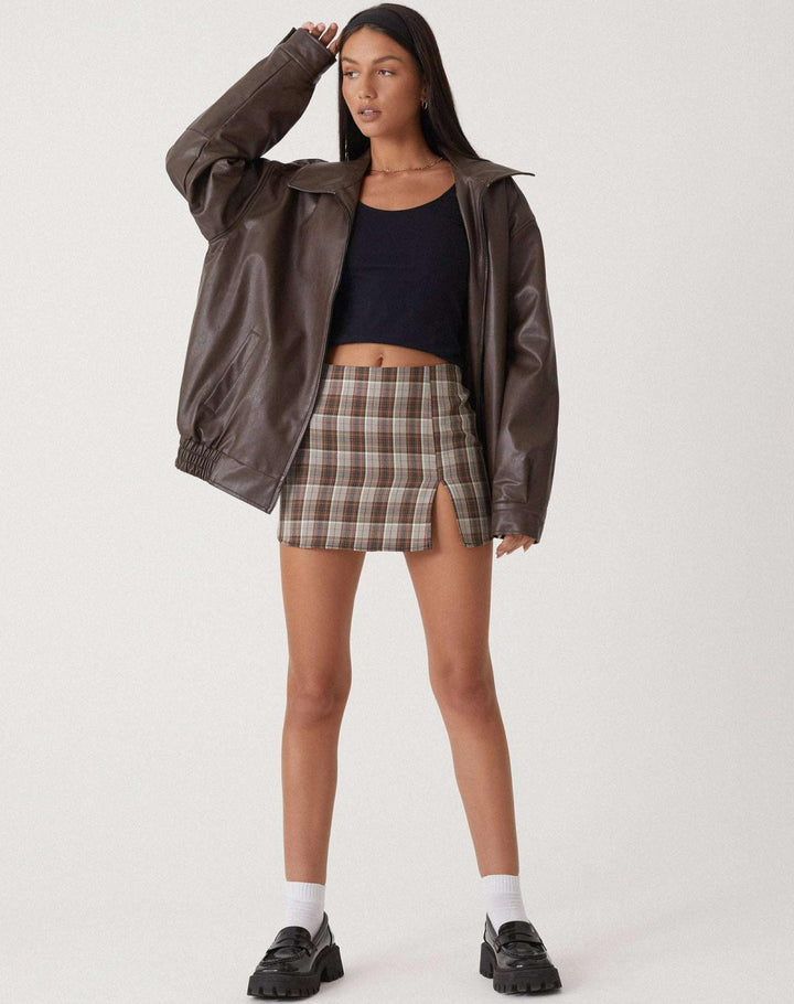 Veste oversize en PU pour femme, modèle Cécile. Veste en simili-cuir marron avec coupe ample, parfaite pour l'hiver. Associée à une jupe à carreaux et des chaussures noires, cette veste élégante et confortable est idéale pour les journées fraîches.