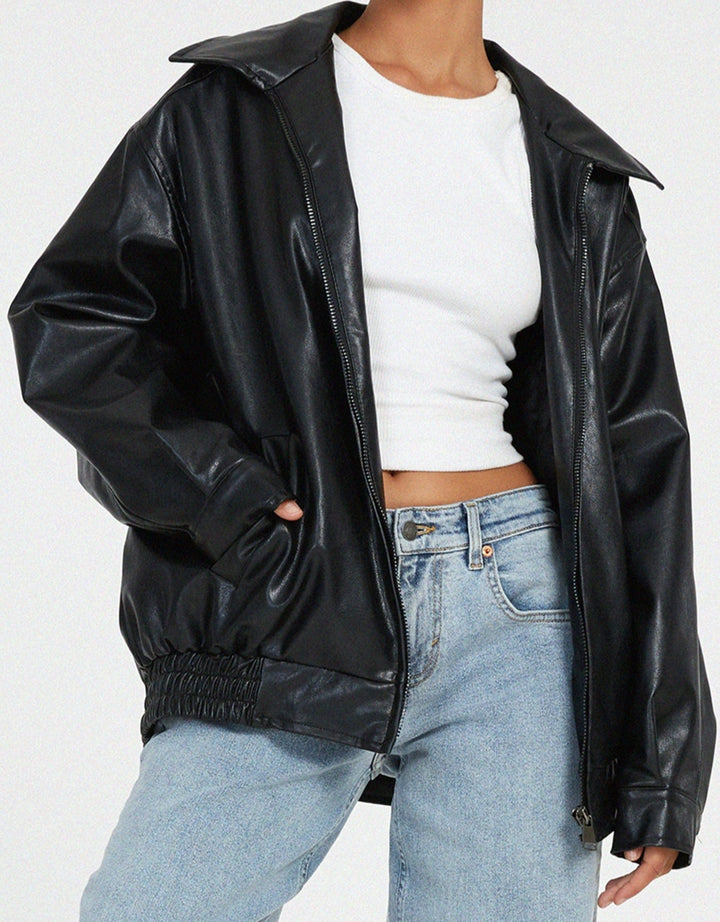 Détail de la veste oversize en PU pour femme, modèle Cécile. Veste en simili-cuir noir avec coupe ample, zippée et taille élastiquée, portée avec un t-shirt blanc et un jean décontracté. Un style moderne et confortable, idéal pour l'hiver.