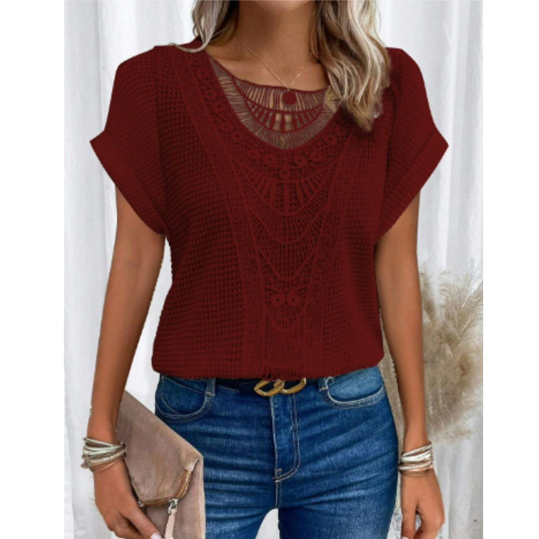 Haut d’été femme Cerise tendance, top bordeaux à manches courtes avec détail en dentelle ajourée au col, coupe fluide, porté avec jean bleu et pochette beige.