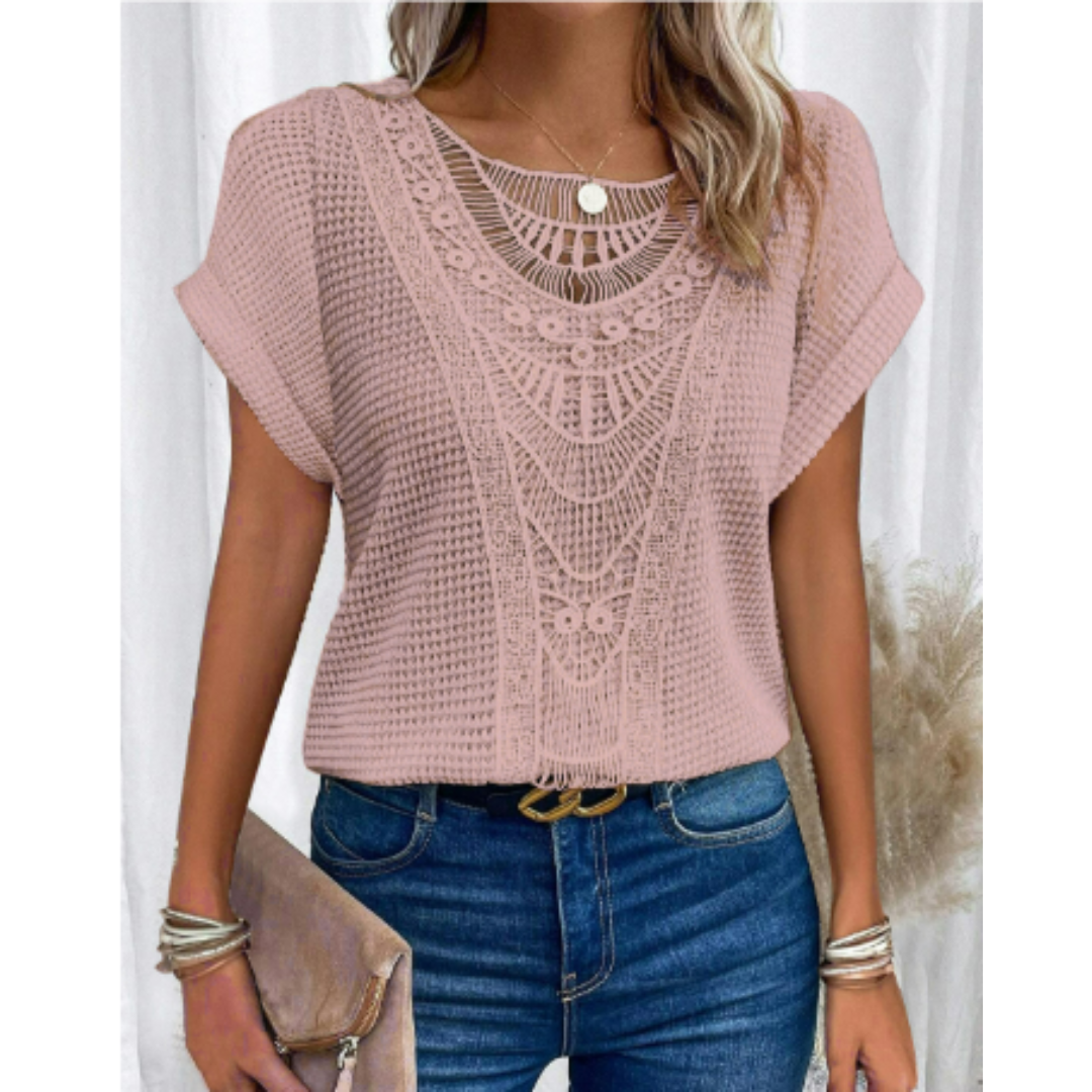 Haut d’été femme Cerise tendance, top rose poudré à manches courtes avec détail en dentelle ajourée au col, coupe fluide, porté avec jean bleu et pochette beige.