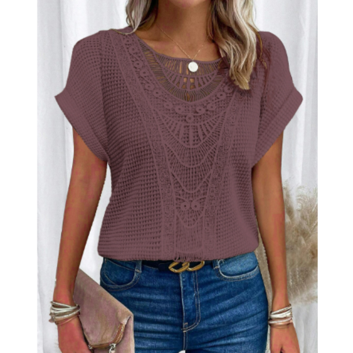 Haut d’été femme Cerise tendance, top violet mauve à manches courtes avec détail en dentelle ajourée au col, coupe fluide, porté avec jean bleu et pochette beige.