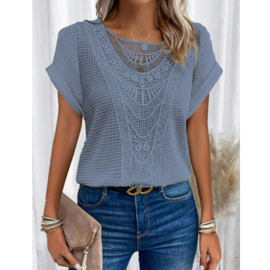 Haut d’été femme Cerise tendance, top bleu clair à manches courtes avec détail en dentelle ajourée au col, coupe fluide, porté avec jean bleu et pochette beige.