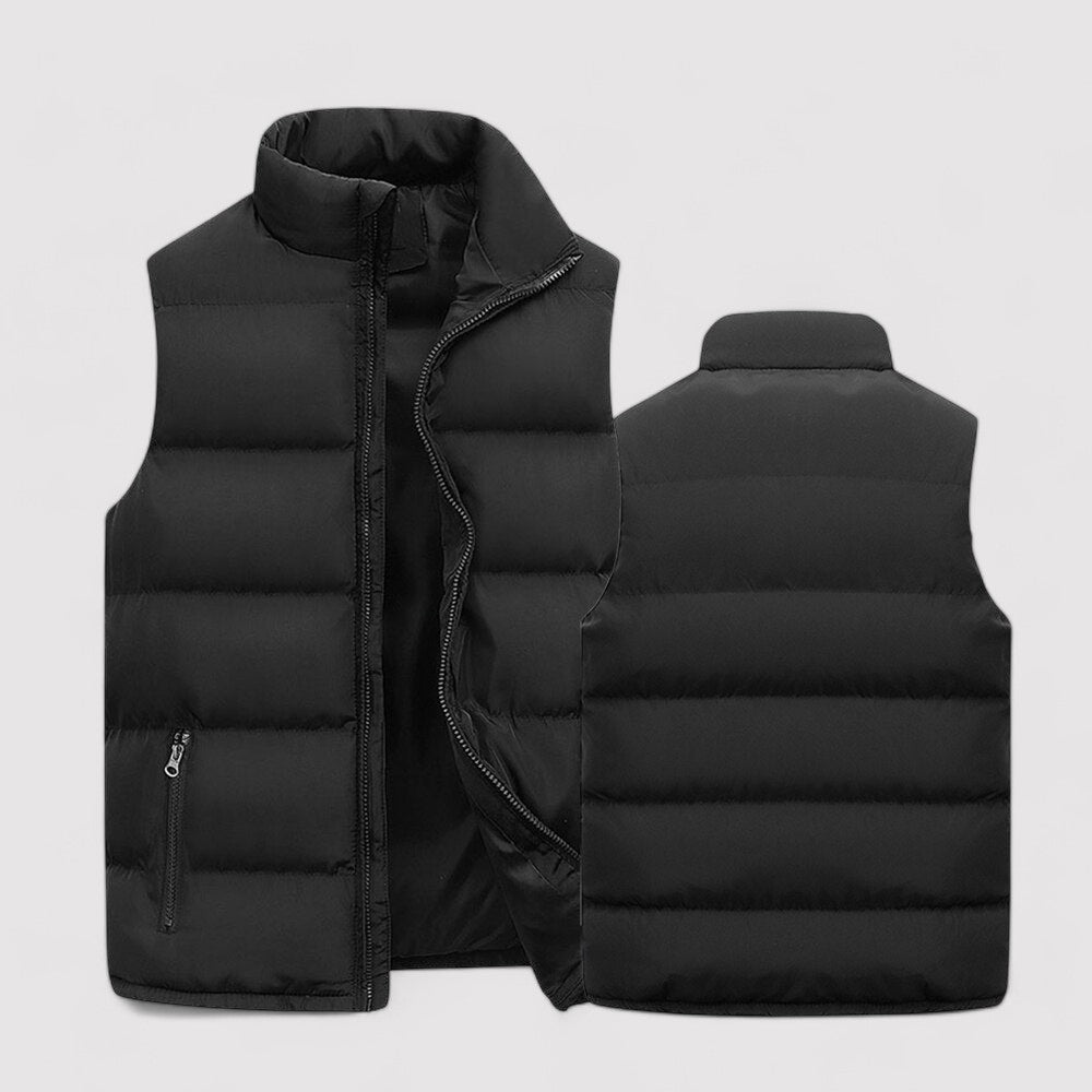Gilet sans manches pour homme de couleur noire, matelassé avec une fermeture éclair centrale. Il présente des poches latérales zippées et un col montant pour plus de confort et de chaleur.