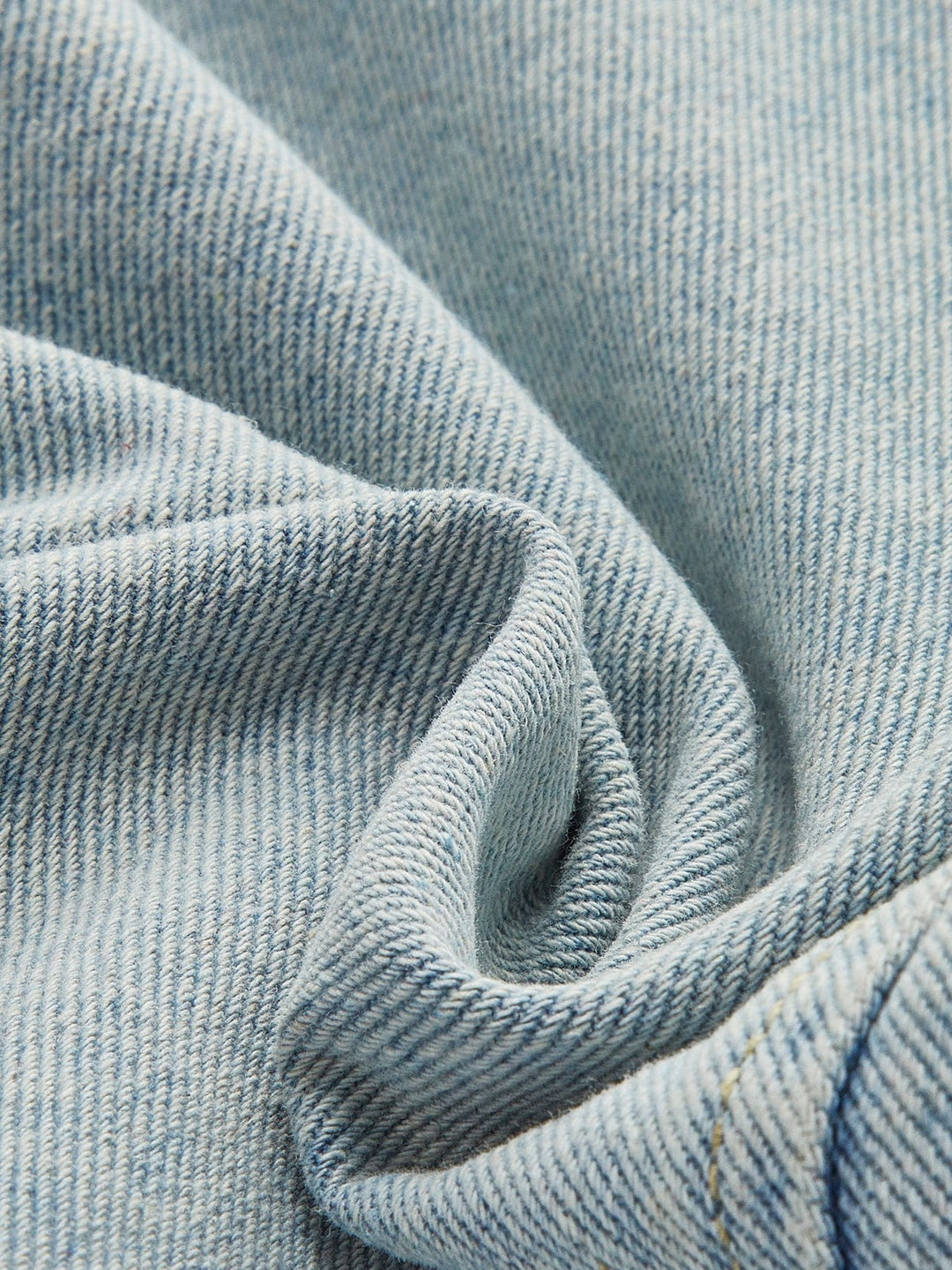 Détail du tissu en denim bleu clair, doux au toucher et de haute qualité, qui compose cette veste courte. Le tissu apporte confort et style tout en étant parfait pour la saison hivernale.