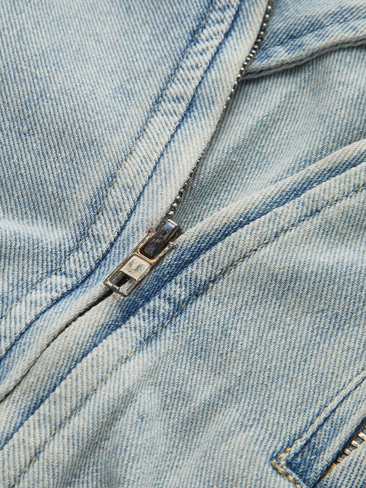 Zoom sur la fermeture éclair métallique de la veste, mettant en avant la qualité et les finitions soignées. Ce détail pratique et stylé ajoute une touche moderne à cette veste en denim idéale pour la saison hivernale.