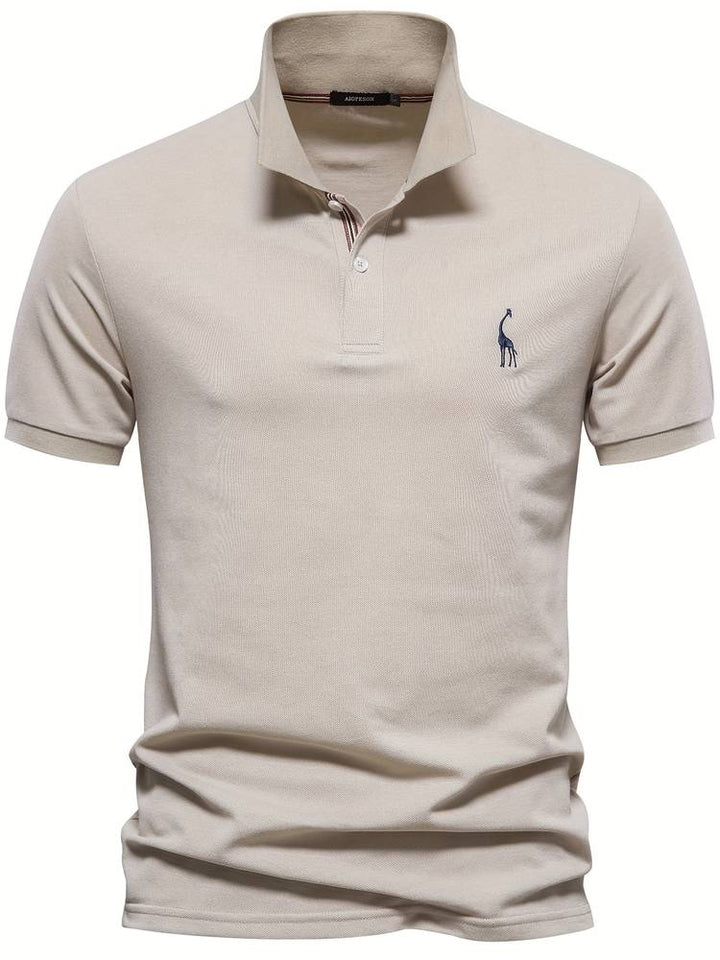 Un polo beige avec un logo de girafe brodé sur la poitrine. Ce modèle au col classique, orné de rayures discrètes à l'intérieur, offre un look à la fois élégant et décontracté, parfait pour un style moderne.